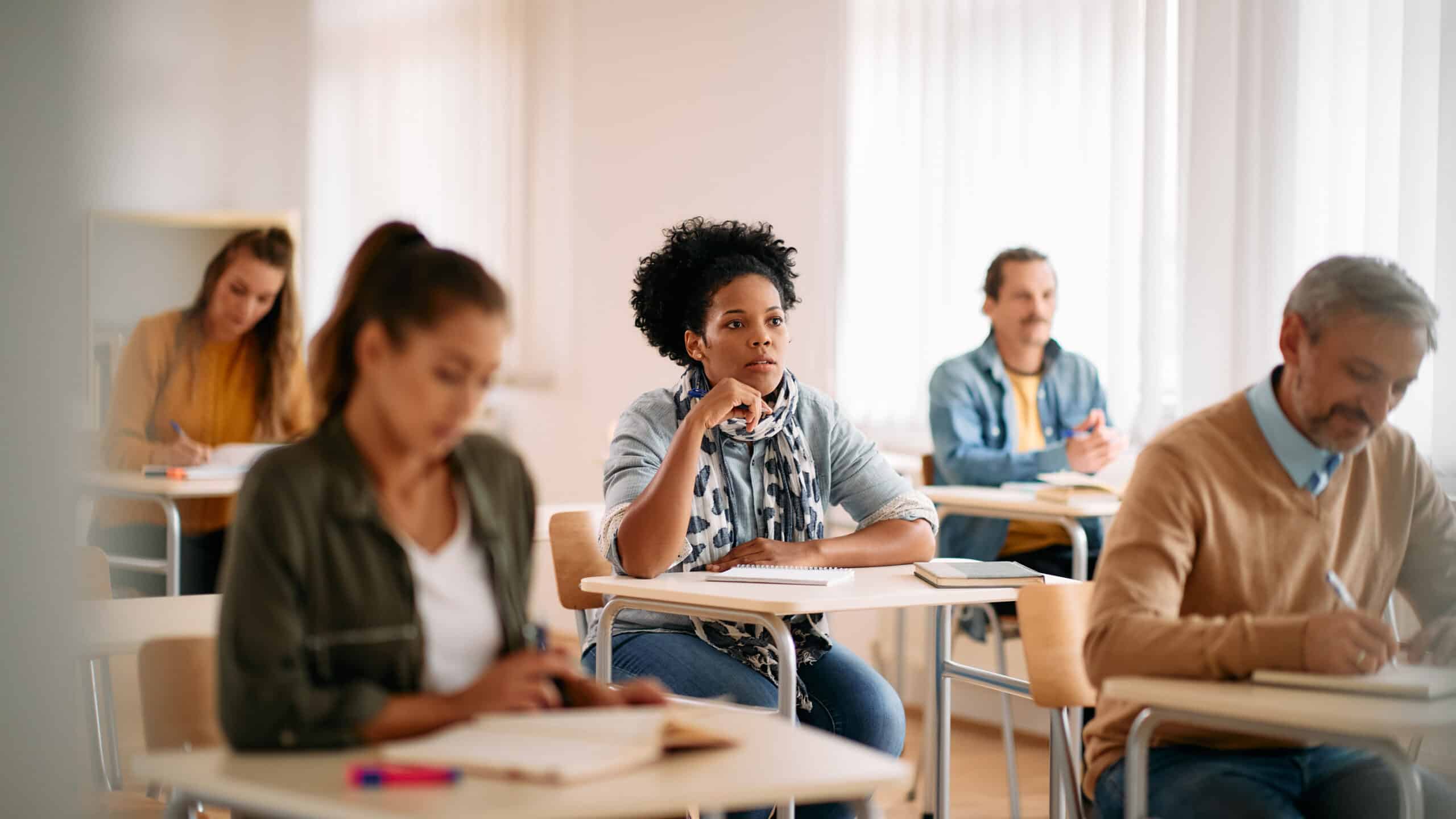 Cert IV in training and assessment - how much does cert iv training and assessment cost in Australia - Black female student paying attention on a class at lecture hall.